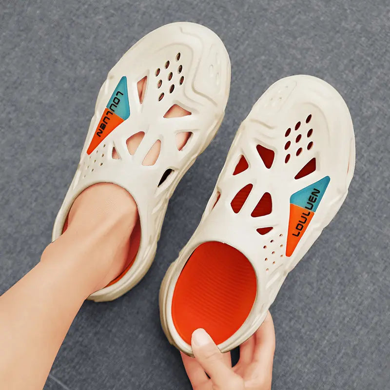 Cream beige EVA clogs with an open heel, featuring a sculpted sole with orange accents and geometric perforations. The interior is lined in vibrant orange, and the side panel displays split orange and blue 'LOULUEN' branding.