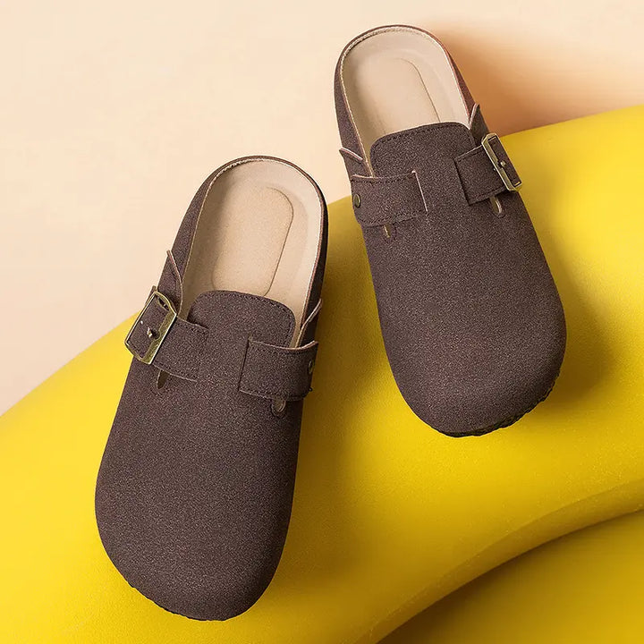 Kaelen taupe suede-effect slip-on mules featuring an adjustable antique brass buckle detail on a textured round toe. These comfortable casual shoes offer a sophisticated look.