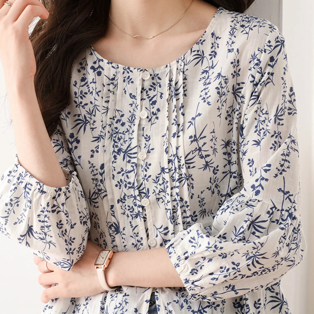 Kaelen women's white cotton blouse with a delicate blue floral print, featuring voluminous three-quarter puff sleeves, a round neckline with pintuck pleats, and a two-button placket.