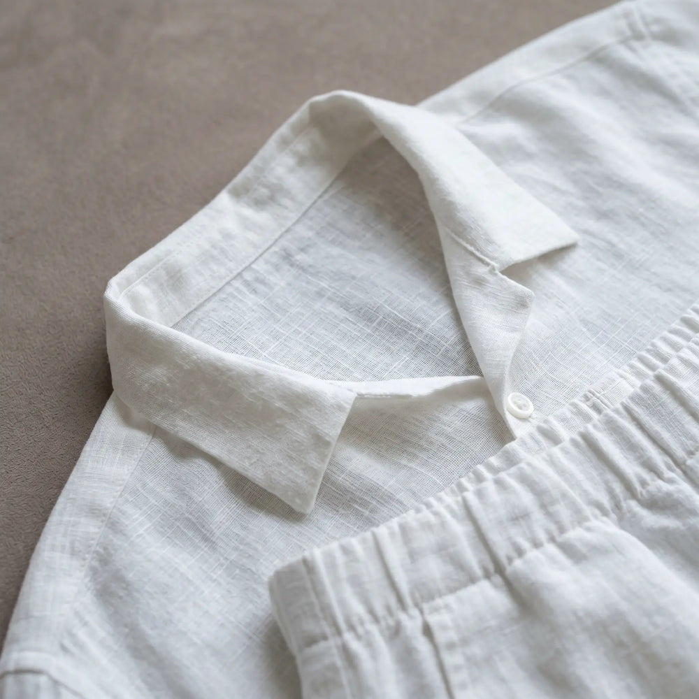Close-up of Kaelen white linen-cotton blend relaxed shirt and wide-leg trousers, showcasing fine slub texture and subtle crinkle detail on the fabric.