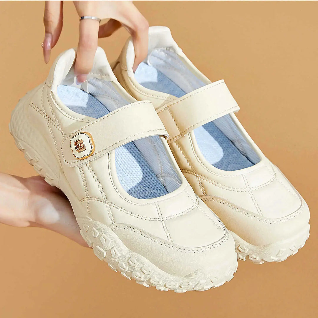 Cream white Kaelis Mary Jane flats with diamond quilting and a single hook-and-loop strap featuring a gold decorative buckle. These soft sole comfort shoes have a chunky rubber sole and a round toe.