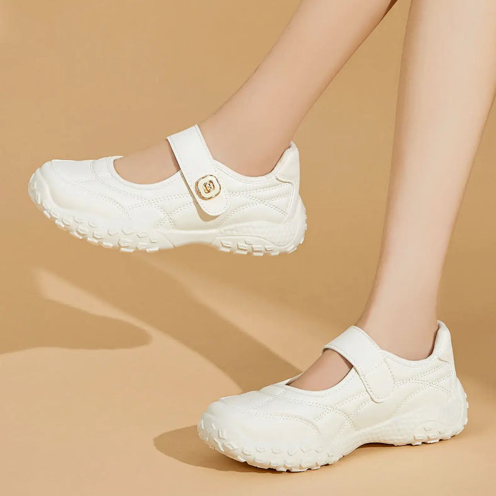 Cream white Kaelis Mary Jane flats with a diamond-quilted synthetic leather upper and a single hook-and-loop strap featuring a gold decorative buckle, shown on a model&