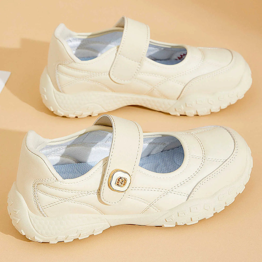 Kaelis cream white quilted Mary Jane flats with adjustable hook-and-loop straps and chunky rubber soles, shown from a three-quarter angle on a neutral studio background.