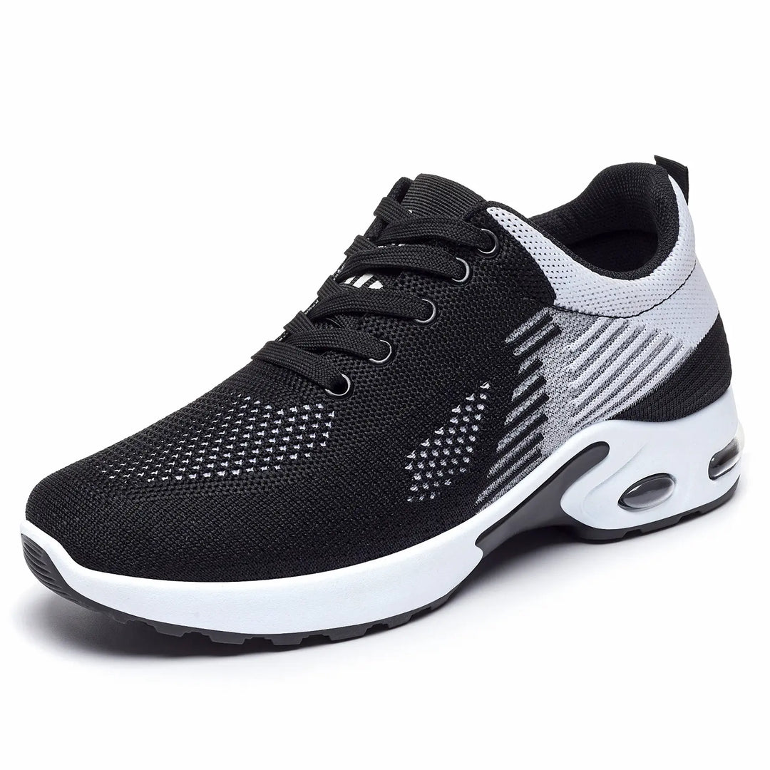 Kaelix breathable knit trainers in black with white and grey abstract stripes, featuring a visible air cushioning unit in the heel, shown in a three-quarter front view.