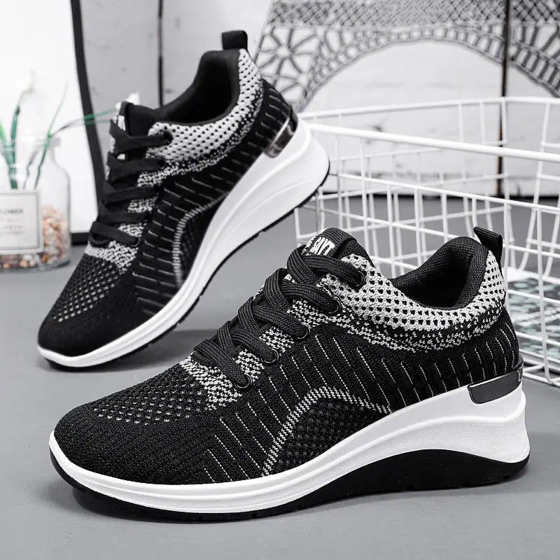 Black and grey Kaelix women's breathable knit sneakers shown from a three-quarter angle, featuring a sculpted white wedge sole and metallic heel accent.