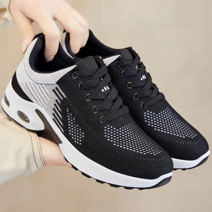 Black and white Kaelix breathable knit trainers with abstract wavy stripe detailing, white laces, and visible air cushioning in the heel.