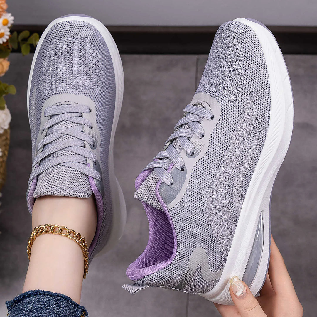 Light grey Kaelix women's breathable mesh trainers with a subtle wave pattern and a contrasting lavender padded collar, shown on foot with a gold chain anklet.
