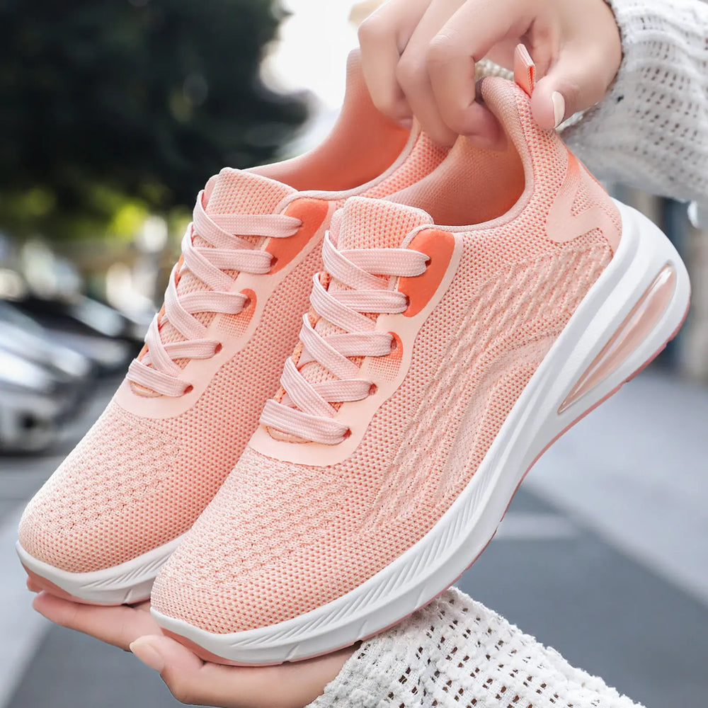 Soft peach Kaelix women's breathable mesh trainers with a cushioned sole and visible air unit, held in hands outdoors.
