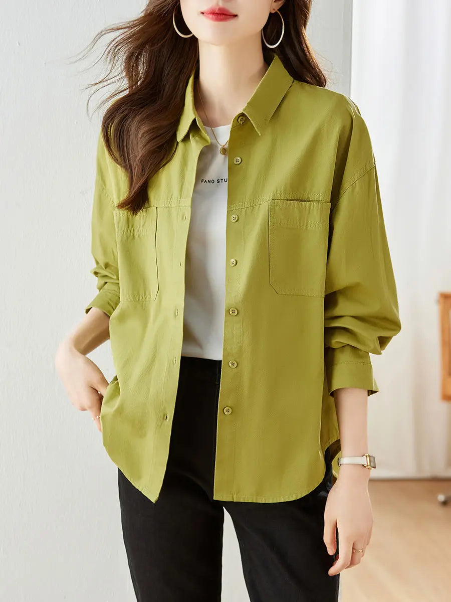 A woman wearing a vibrant Yuzu Green Kaelix cotton shirt with a relaxed fit, polo collar, and dual chest pockets, layered over a white t-shirt. She is shown from the front with her hands in her pockets.