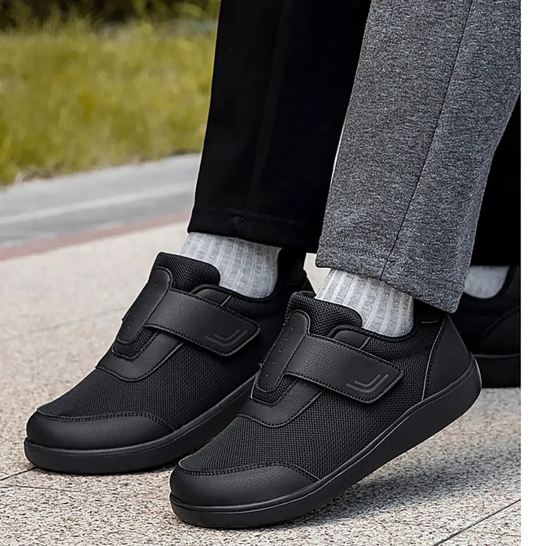 Black mesh walking shoes with hook-and-loop straps worn by individuals outdoors, showcasing their comfort and breathable design.