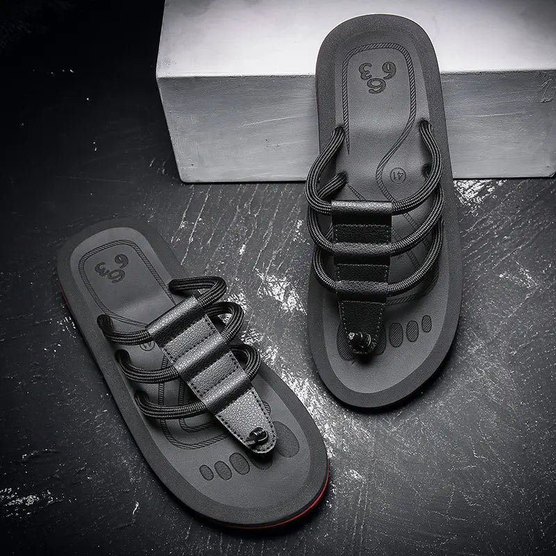 Black Kaelo men's EVA slides with multi-strand fabric straps and a faux leather accent, shown from a three-quarter angle on a textured studio background.