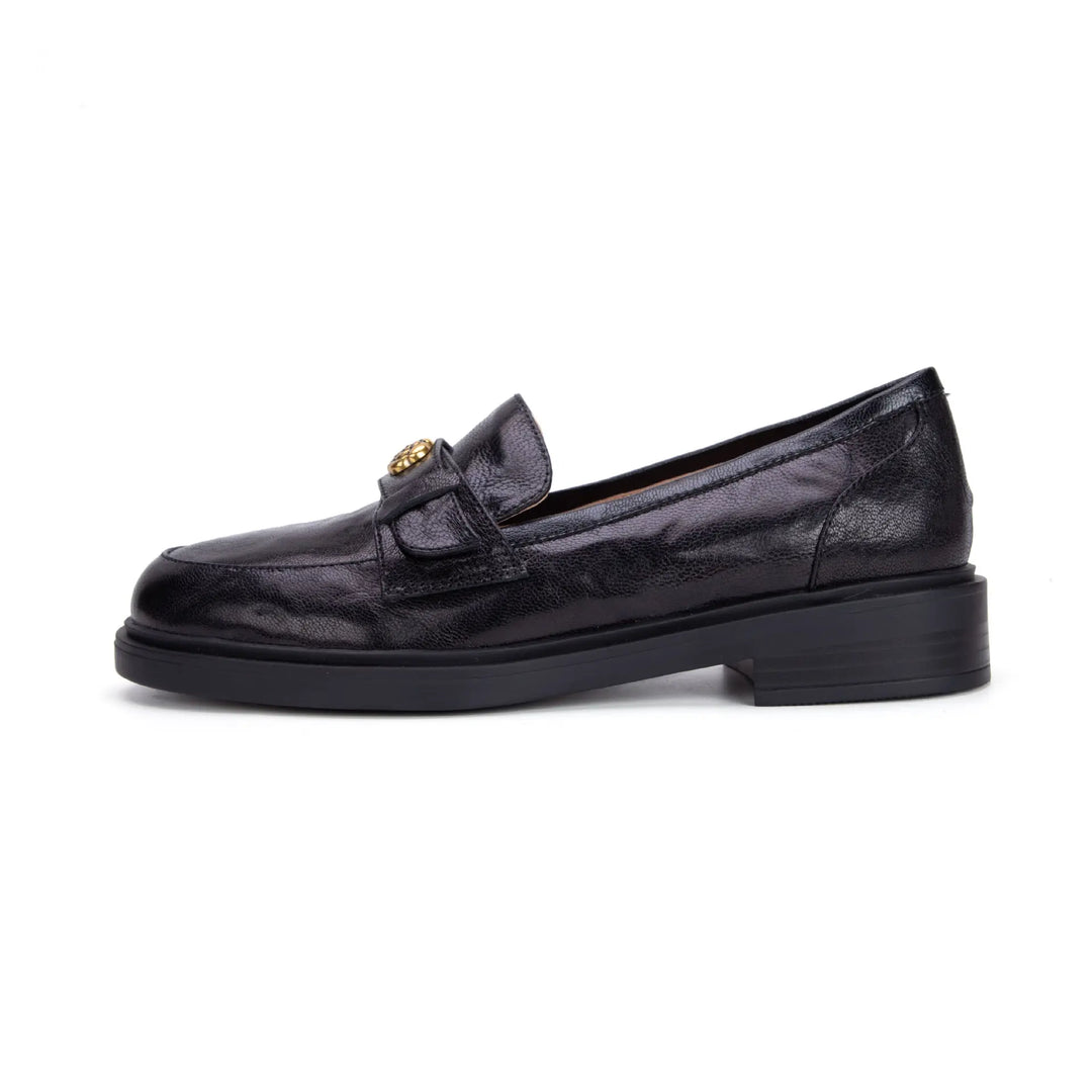 Side view of a black Kaelos sheepskin leather loafer featuring a round toe, low block heel, and a decorative floral-embellished buckle on the strap.