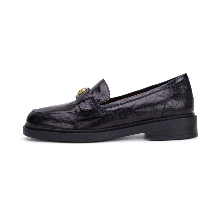 Side view of a black Kaelos sheepskin leather loafer featuring a round toe, low block heel, and a decorative floral-embellished buckle on the strap.