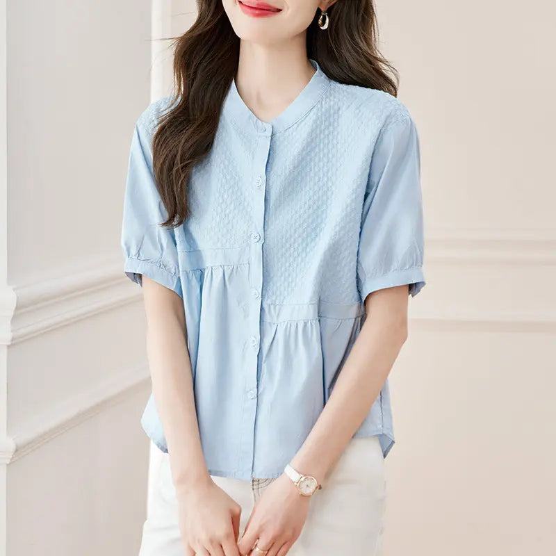 Chic Kaelos powder blue cotton blouse with woven chest panel, mandarin collar, short puff sleeves, and peplum hem, shown on a model.