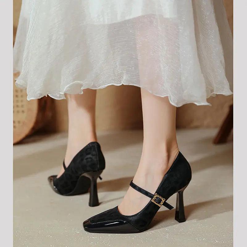 Black patent leather and leopard print suede Mary Jane heels with a square toe and gold buckle strap, shown on feet.