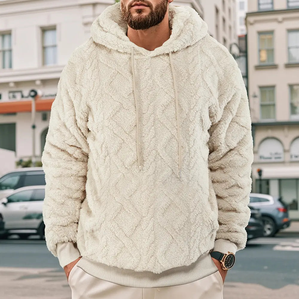 Men's Kaelum creamy ivory textured fleece hoodie with a chevron pattern, worn by a model in an urban outdoor setting. Features a drawstring hood and kangaroo pocket.