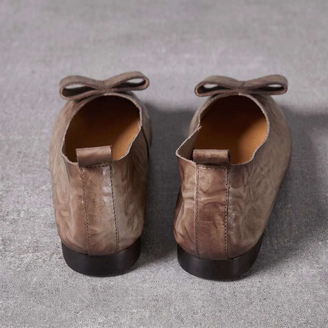 Kaelum grey leather ballerina flats with pointed toe and decorative bow accent, shown from the back with heel pull tabs.