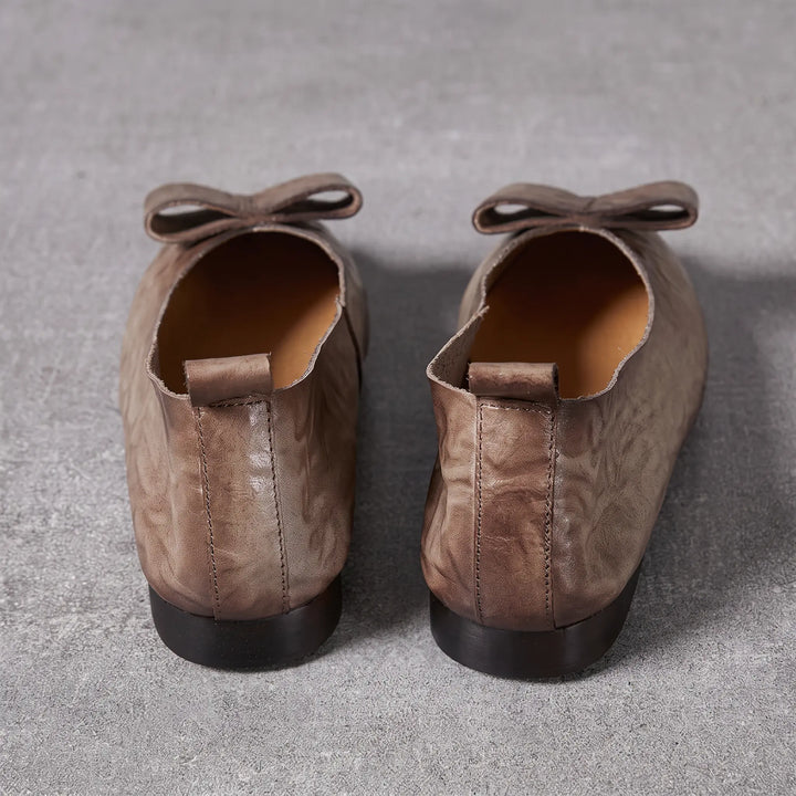Kaelum grey leather ballerina flats with pointed toe and decorative bow accent, shown from the back with heel pull tabs.