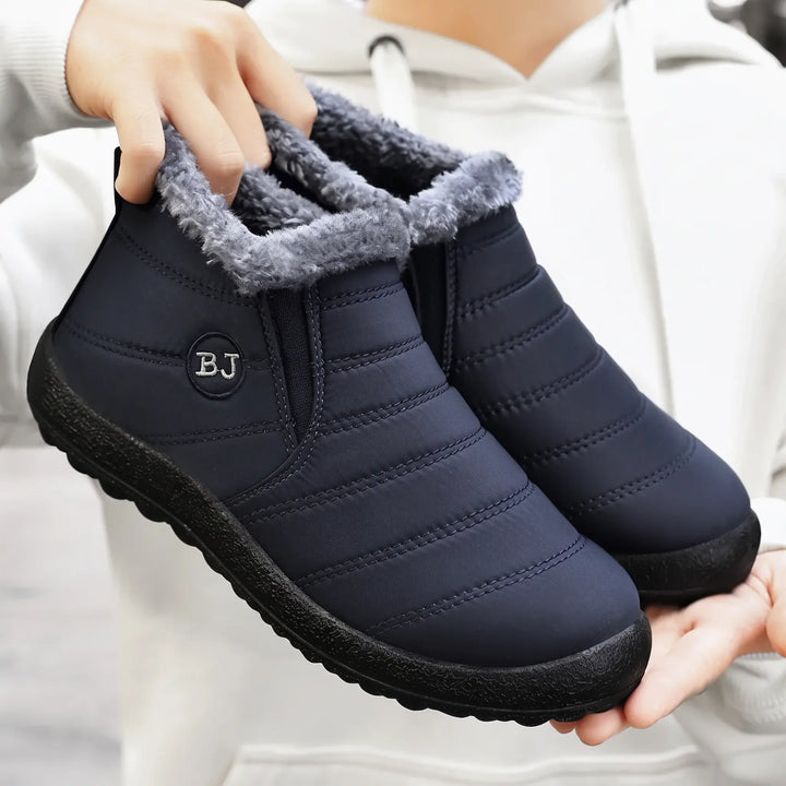 Dark navy blue Kaelum winter boots for unisex adults, featuring a quilted water-resistant upper, warm grey faux fur lining, elasticated side gussets for slip-on wear, and a flat lugged rubber sole.