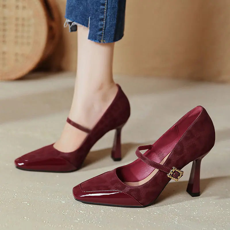 Kaelum patent leather Mary Jane heels in wine red, featuring a square toe and decorative gold buckle strap, worn with denim.