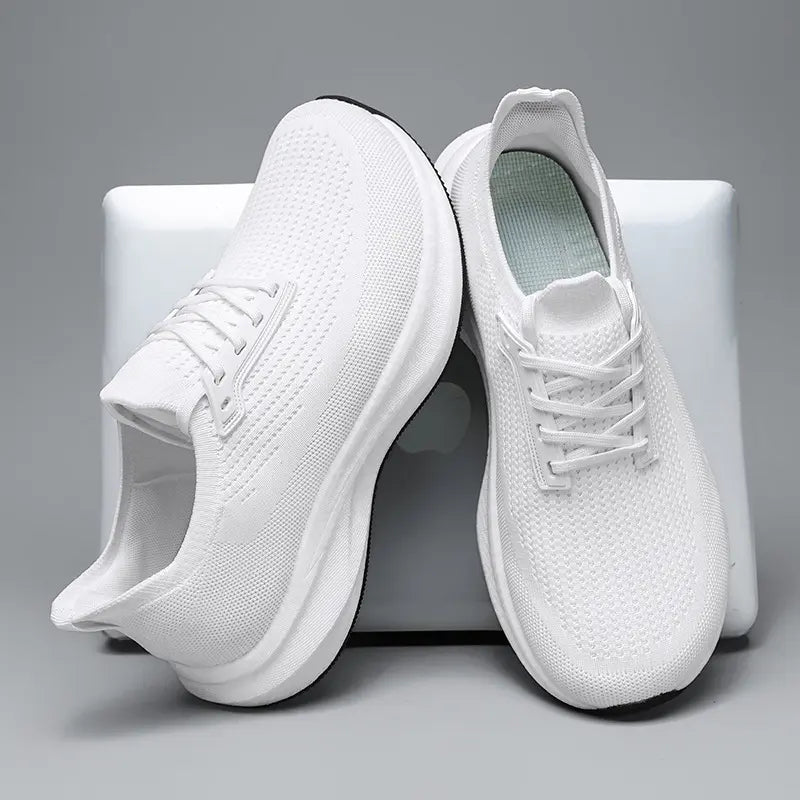 Side three-quarter view of white Kalyx wide fit breathable trainers, showcasing the engineered mesh upper, lace-up front, and thick white EVA midsole with black rubber outsole.
