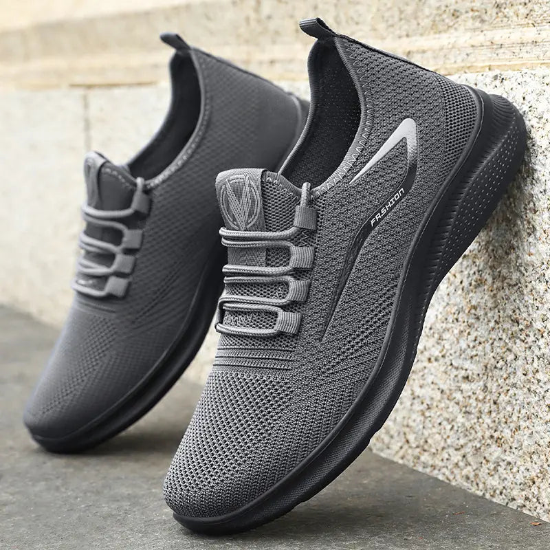 Medium-grey engineered knit men's sneakers with a subtle reflective side accent featuring 'FASHION' text and a matte black sculpted PU sole.