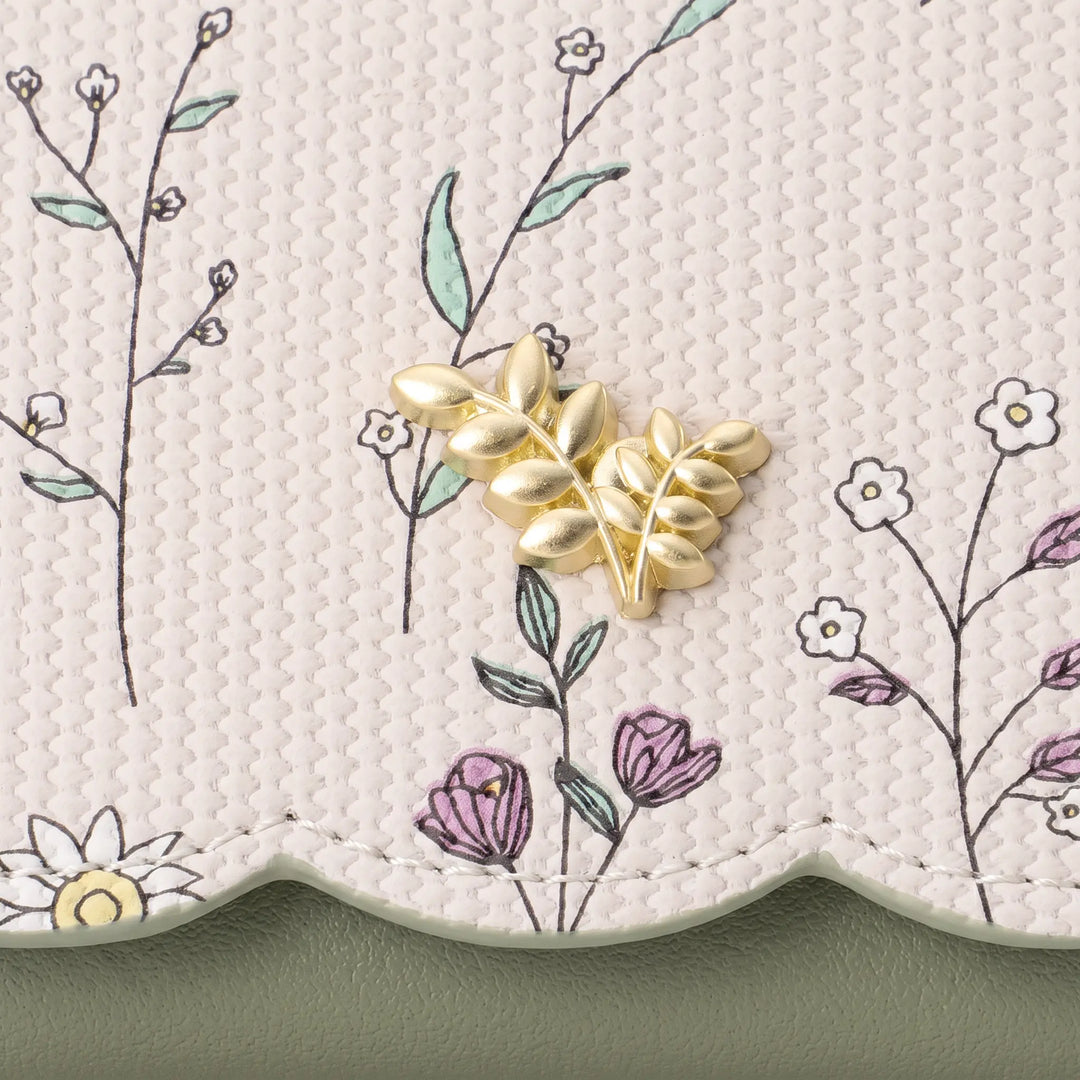 Close-up view of a Kezel PU leather wallet showcasing a delicate floral print with light green stems and white daisies, accented by a gold-tone metal flower charm.