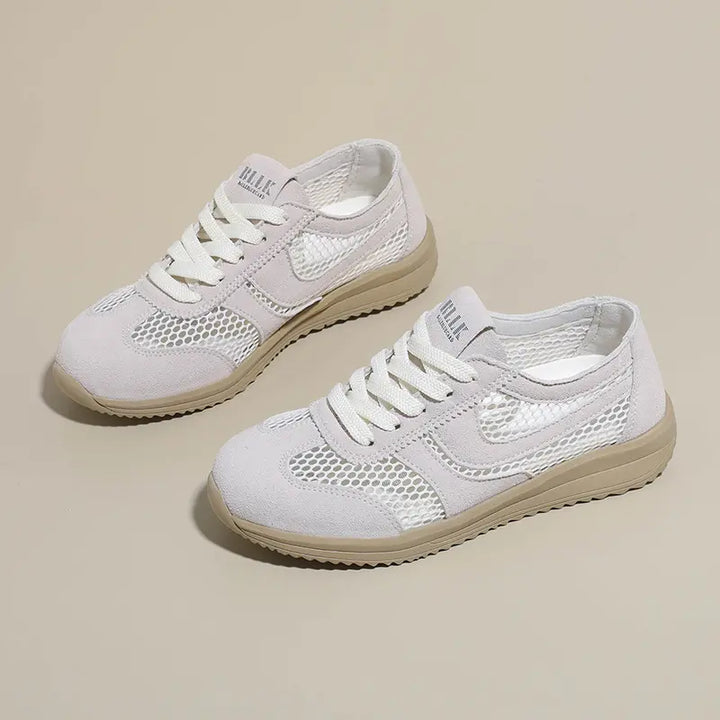 Two off-white breathable mesh trainers with suede-like accents and light beige soles, shown from a three-quarter angle on a neutral studio background.