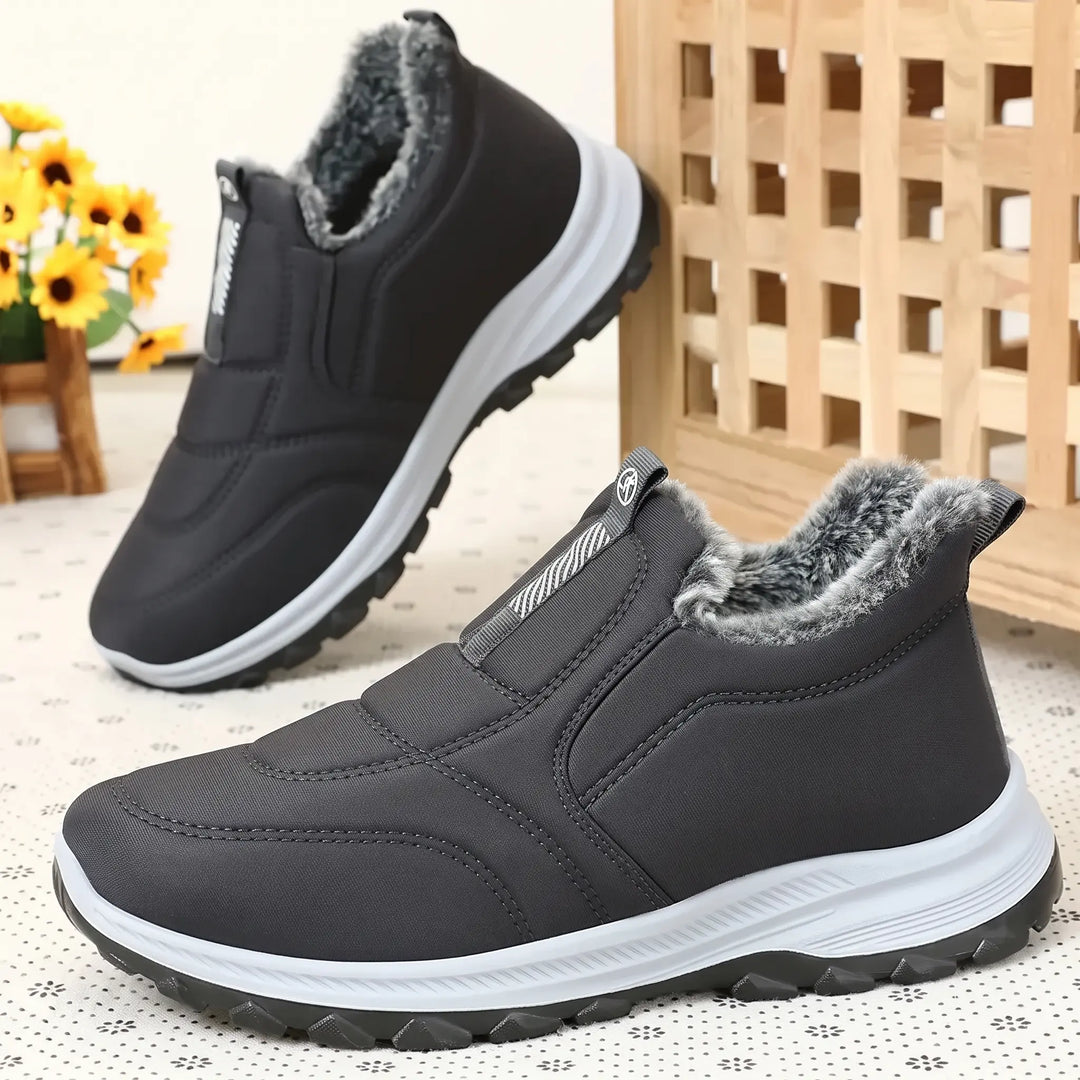 A pair of dark grey, mid-calf winter boots with a quilted Lycra upper and fluffy faux fur lining. Shown from multiple angles on a patterned background with decorative elements.