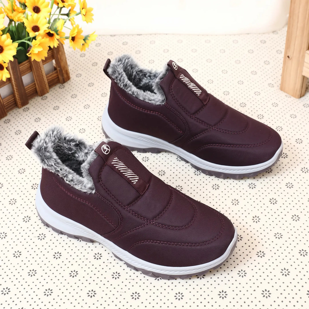 Pair of Kivon unisex mid-calf winter boots in deep red quilted Lycra with fluffy grey faux fur lining and a two-part white and red sole.