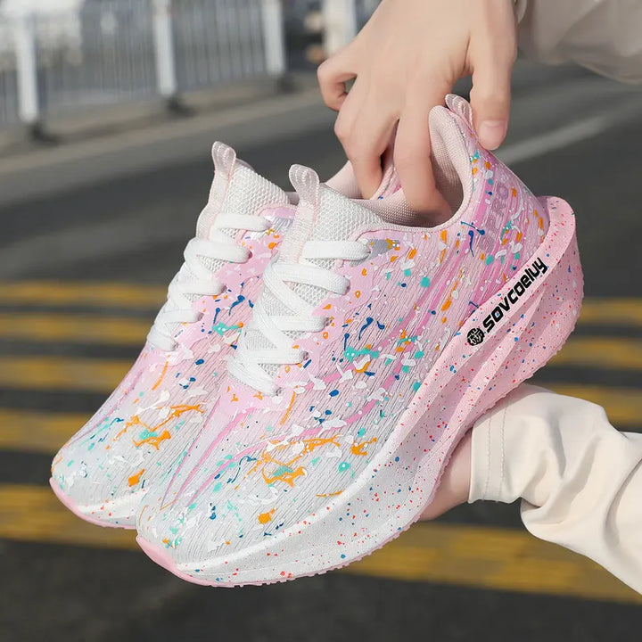Pair of Krytox running shoes in pink with a vibrant multi-color paint splash pattern, showcasing the sculpted speckled midsole and side branding.