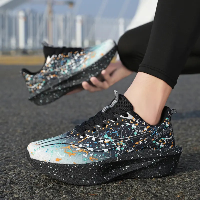 Dynamic Krytox running shoes with vibrant multi-color paint splash design on a black engineered mesh upper, shown on a foot in an active outdoor setting. The sculpted, speckled midsole provides cushioning and support for performance.