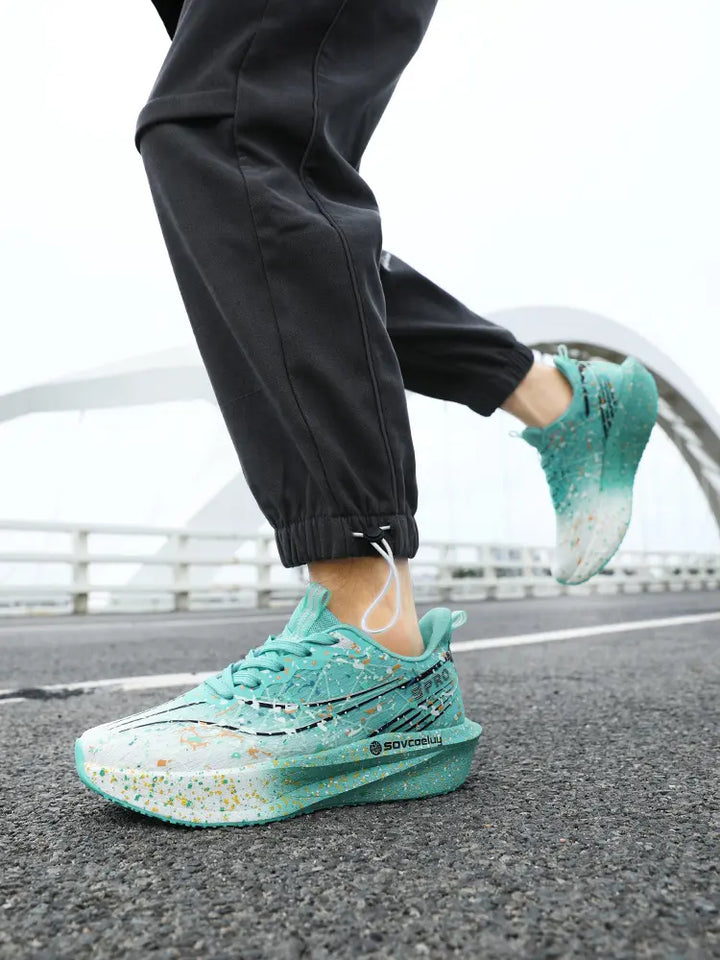 Performance running shoes in a vibrant teal paint splash design, worn by a person in motion on a road with a bridge in the background. Features a sculpted, speckled midsole and dynamic athletic style.