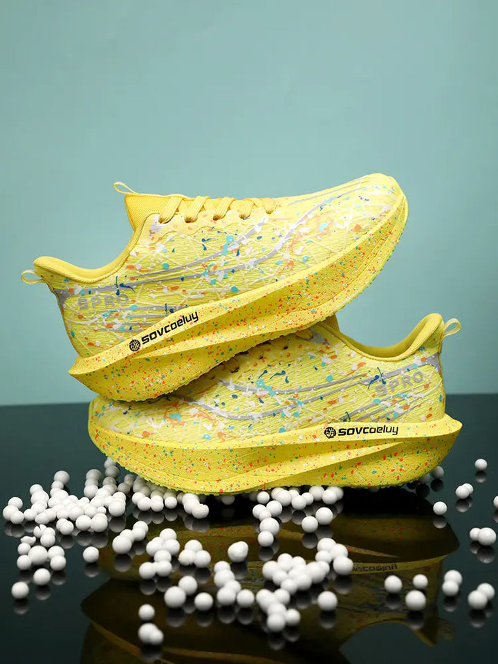 Krytox yellow running shoes featuring a vibrant multi-color paint splash pattern on the engineered mesh upper and sculpted, speckled midsole. These lightweight speed trainers are shown from a three-quarter angle, with subtle &