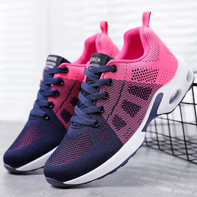 Pair of Kryxa women's lightweight mesh sneakers in vibrant violet and navy blue, featuring a breathable engineered mesh upper, visible air cushion sole, and lace-up closure. Presented on a studio background.