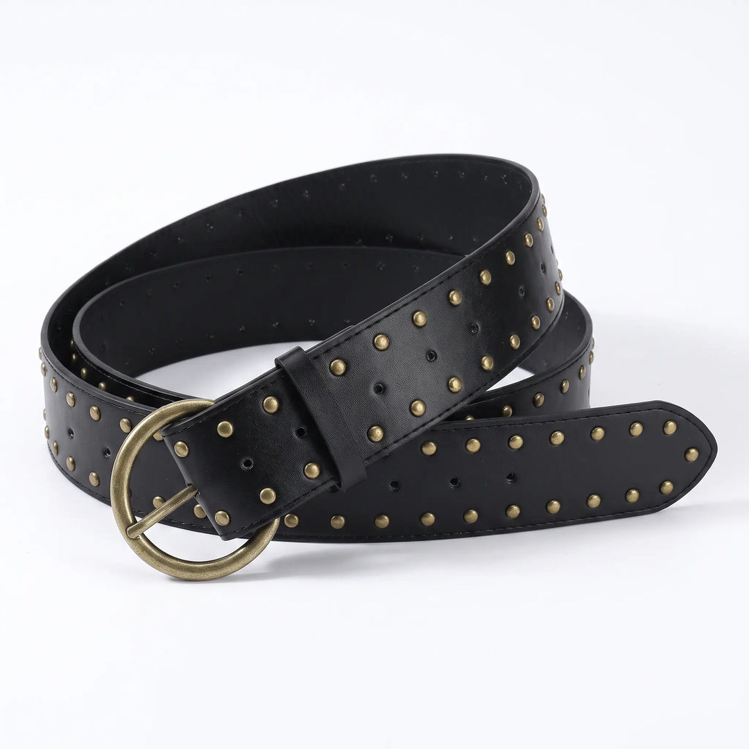 Kryxell wide black PU leather studded belt with antique brass D-ring pin buckle, featuring uniform small metallic studs across the entire surface for a punk-inspired statement accessory.