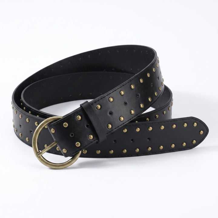 Kryxell wide black PU leather studded belt with antique brass D-ring pin buckle, featuring uniform small metallic studs across the entire surface for a punk-inspired statement accessory.