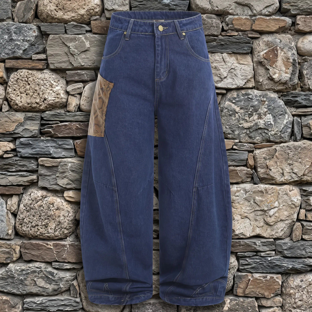 Kylath dark wash wide leg jeans featuring a distinctive faux-snakeskin panel on the upper left thigh and tonal stitching, shown in a front studio view.