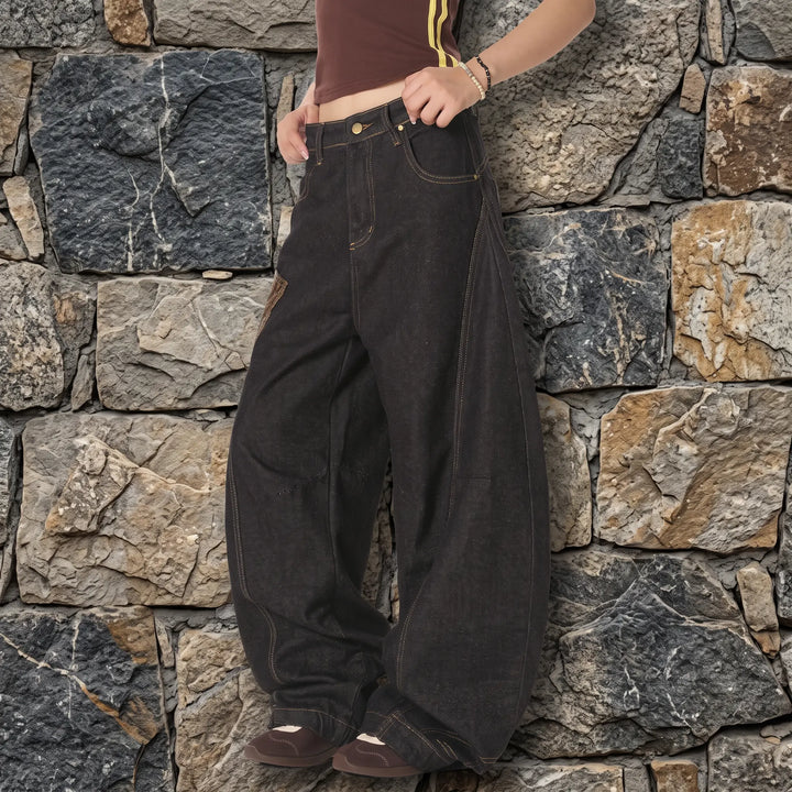 Kylath wide leg jeans in dark wash denim featuring a striking snake print panel on the thigh and a floor-length, voluminous silhouette, shown from a three-quarter side view.