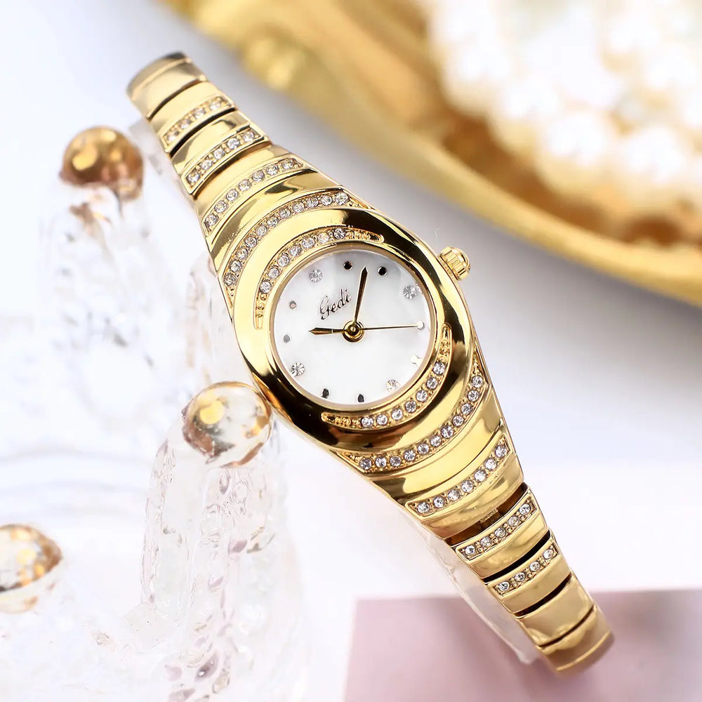Kzira women's gold-tone oval bracelet watch featuring a white dial and sparkling crystal embellishments along the bezel and integrated bracelet.