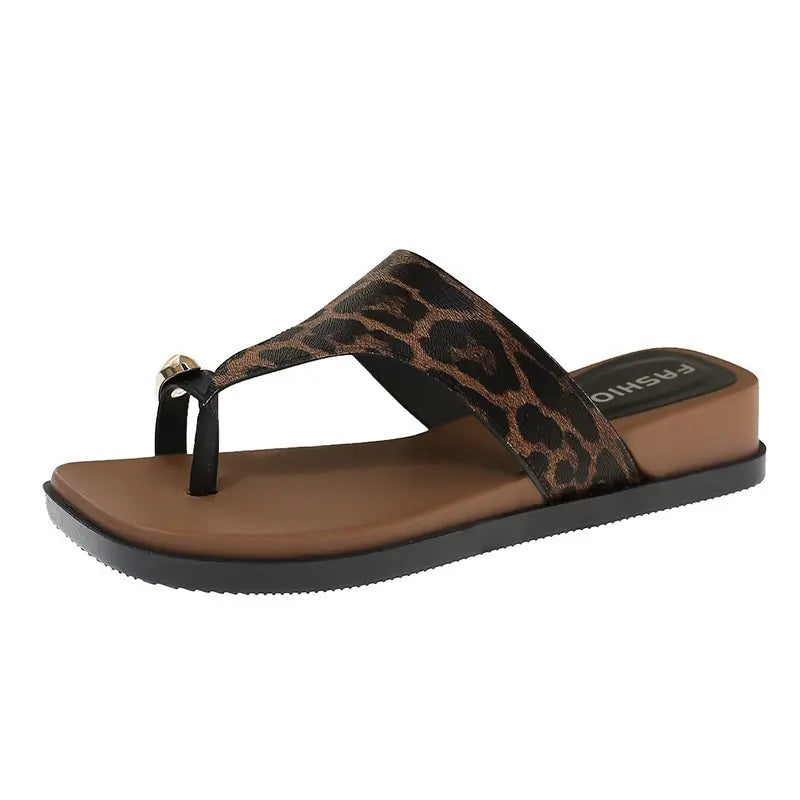 Leopard print thong sandal with a square toe, gold knot accent, and thick black platform sole. Features a brown footbed with white &