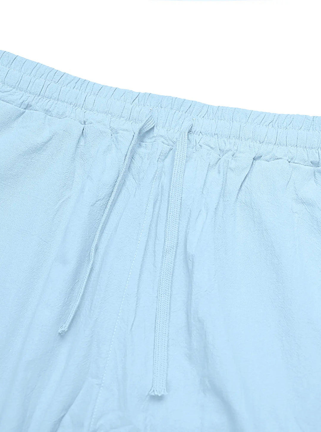 Close-up view of light blue linen-blend trousers showcasing the drawstring, elasticated waistband, and subtle slub texture characteristic of the fabric.