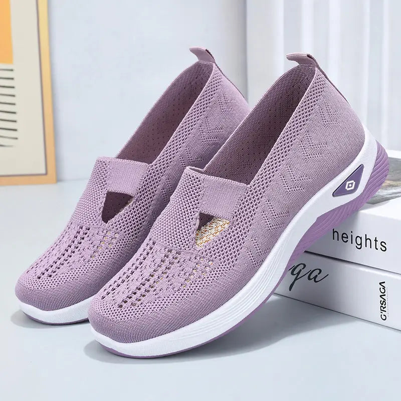 A pair of light purple breathable knit slip-on sneakers with a geometric weave pattern and white cushioned midsole shown from a three-quarter angle.