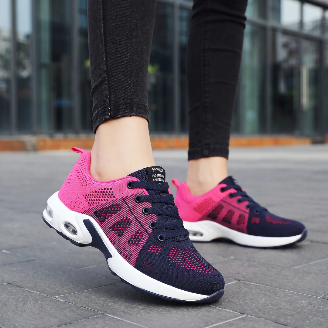 Pink and navy lightweight mesh sneakers with visible air cushion sole, shown on feet in a lifestyle outdoor setting.