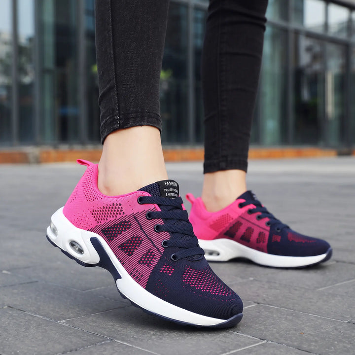 Pink and navy lightweight mesh sneakers with visible air cushion sole, shown on feet in a lifestyle outdoor setting.