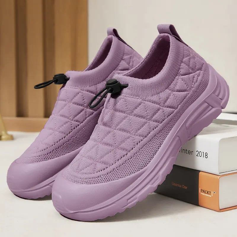 Lilac quilted knit slip-on sneakers with a bungee lace toggle, cream rubber toe cap, and thick white platform sole, viewed from a three-quarter angle.