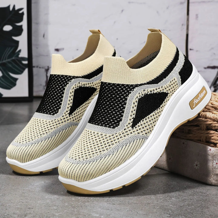 LyraFit breathable knit slip-on sneakers in warm beige with black and grey wavy stripe details and a white platform sole featuring the &