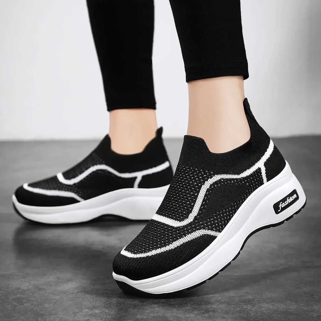Black LyraFit knit slip-on sneakers with white wavy accents and a thick white platform sole featuring the &