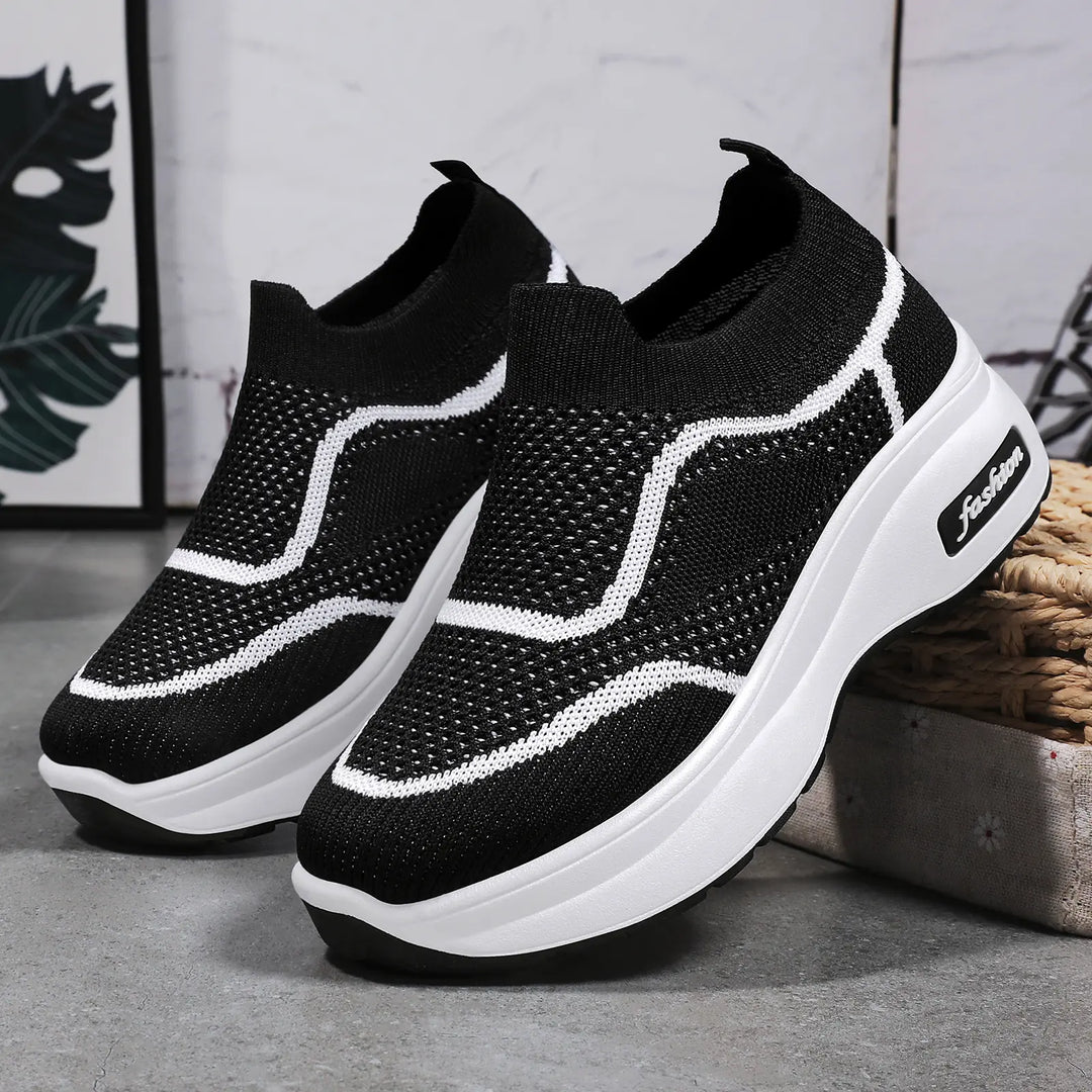 Black LyraFit knit slip-on sneakers with white wavy stripe detailing and a thick white platform sole featuring a &
