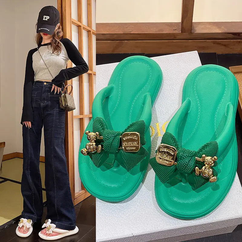Women's green Lyraku flip-flops with bow and teddy bear charm, shown on a model and as a close-up studio shot.
